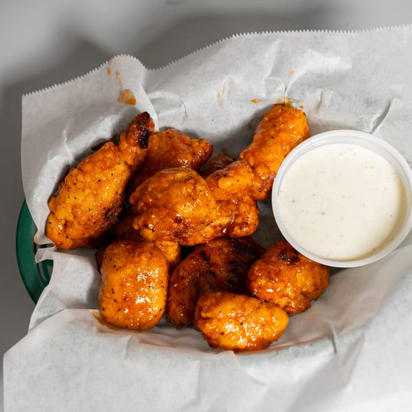 Ruszoni's boneless wings, coated in orange sauce, served in a basket with a side of ranch.