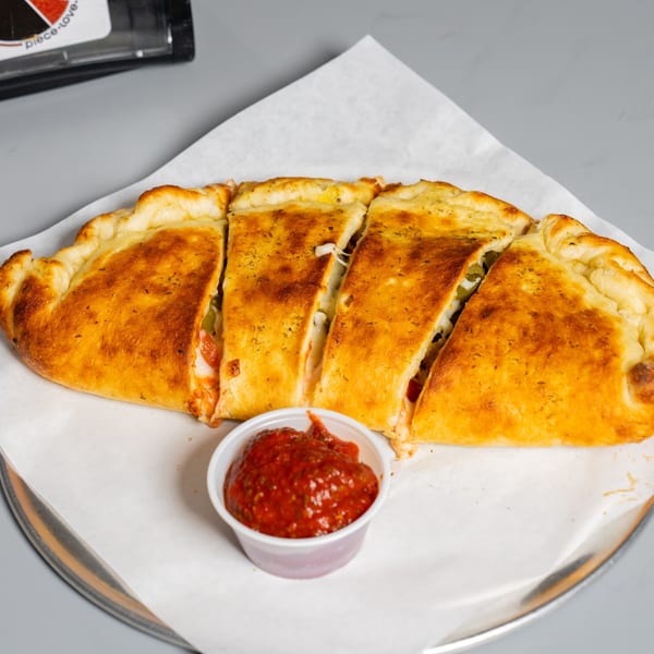 Golden-brown Ruszoni's calzone, sliced into four pieces, with a side of marinara sauce.